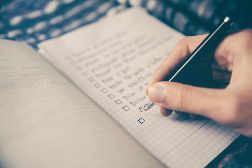 Personne rédigeant une liste de choses à prévoir avant son voyage. La planification de son voyage est une tendance de voyage en 2023.